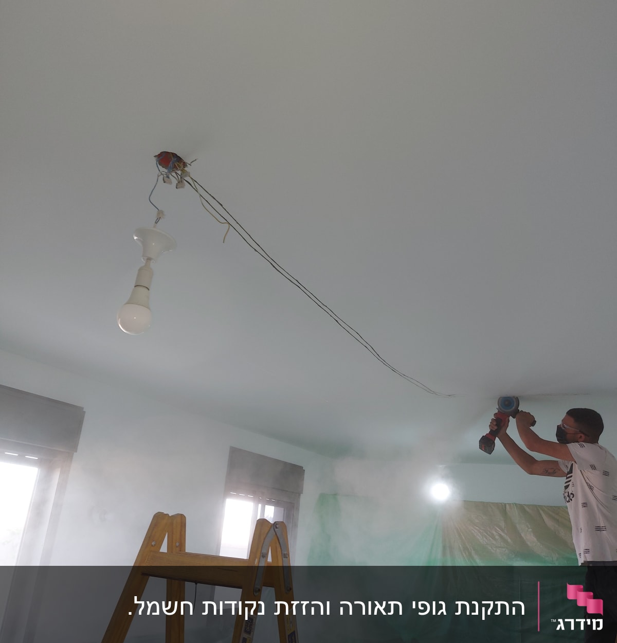 חשמלאי עובד על תקרה עם מקדחה חשמלית